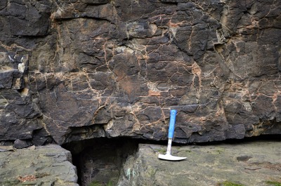Pukliny ve vyvřelé hornině jsou vyplněné druhotnými převážně karbonátovými minerály.